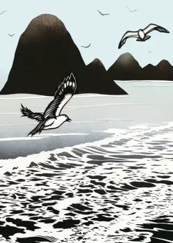 Sea side with mountains in the distance and seagulls flying above