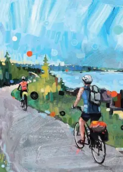 two bicycle riders on paved path next to blue lake and sky